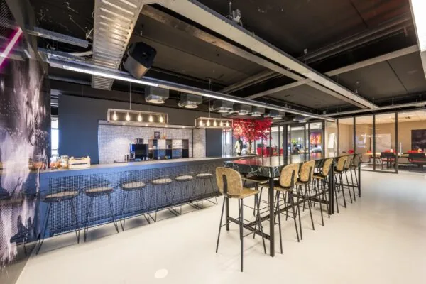 Moderne kantine aan de Anthony Fokkerweg met hoge zitplekken, koffiemachine en sfeervolle verlichting.